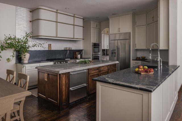Every detail in this kitchen is doing something different... wood tones, brass finishes, two different stones, layered textures. Nothing matches on purpose. And somehow, it all just works.⁠⁠The Monarch hood is the staple of the space, an unmistakable focal point. The island wears its own stone, lighter and veined, standing apart from the moodier stone grounding the perimeter counters. Contrast, on purpose. That same perimeter stone then climbs the wall, forming the perfect little shelf where the backsplash takes over.⁠⁠Functional. Beautiful. Impossible to separate one from the other.